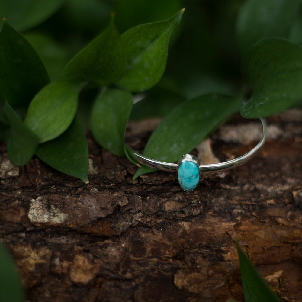 Sierra Nevada turquoise set on silver cuff sitting in woods