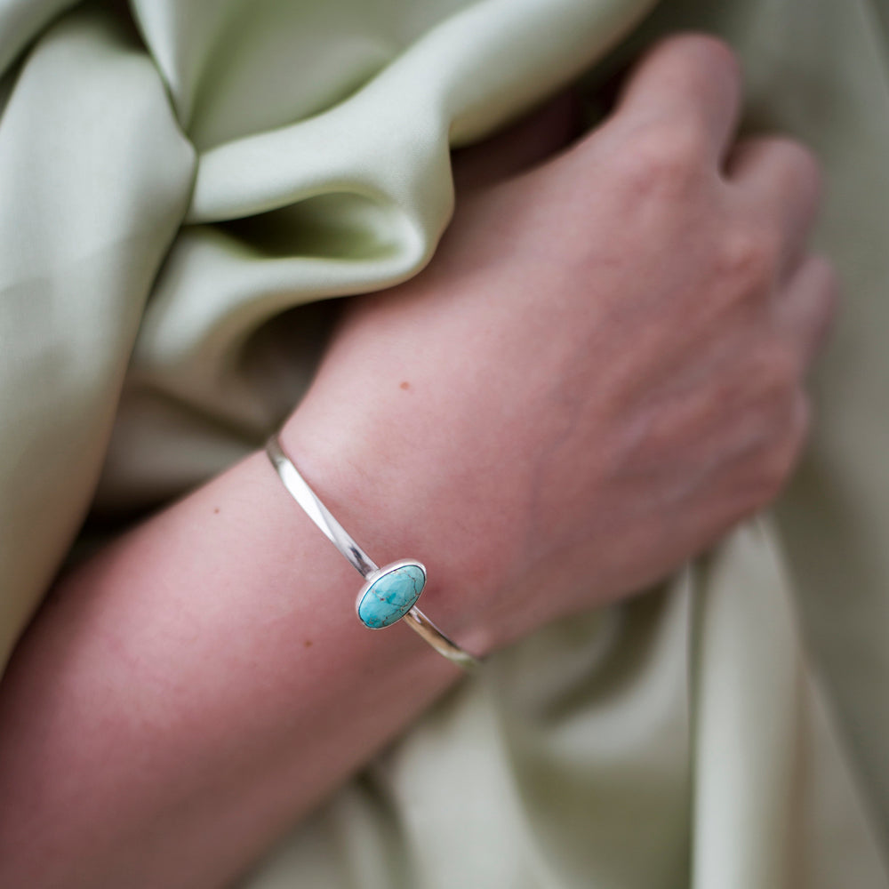 Arm draped across body wearing Turquoise and silver cuff